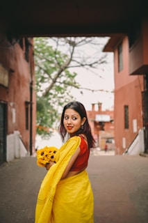 a woman in a yellow dress holding a bouquet of flowers