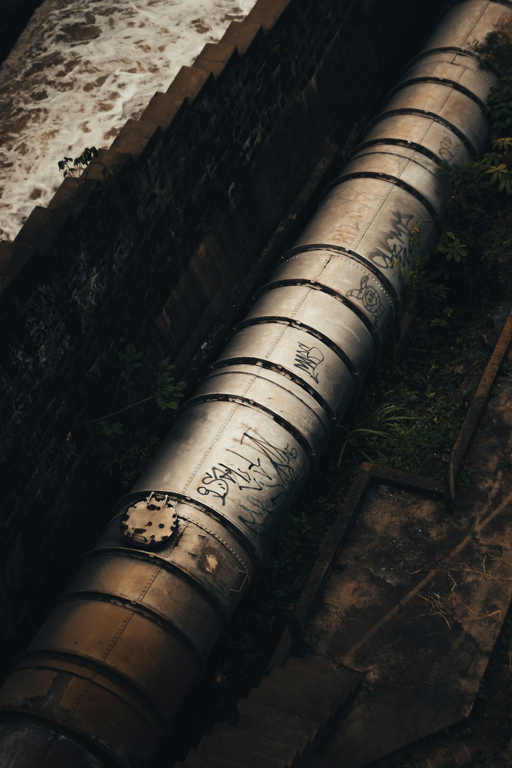 a large metal pipe sitting next to the ocean