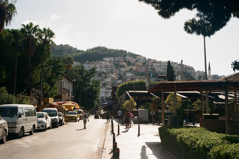 a group of people walking down a street next to parked cars