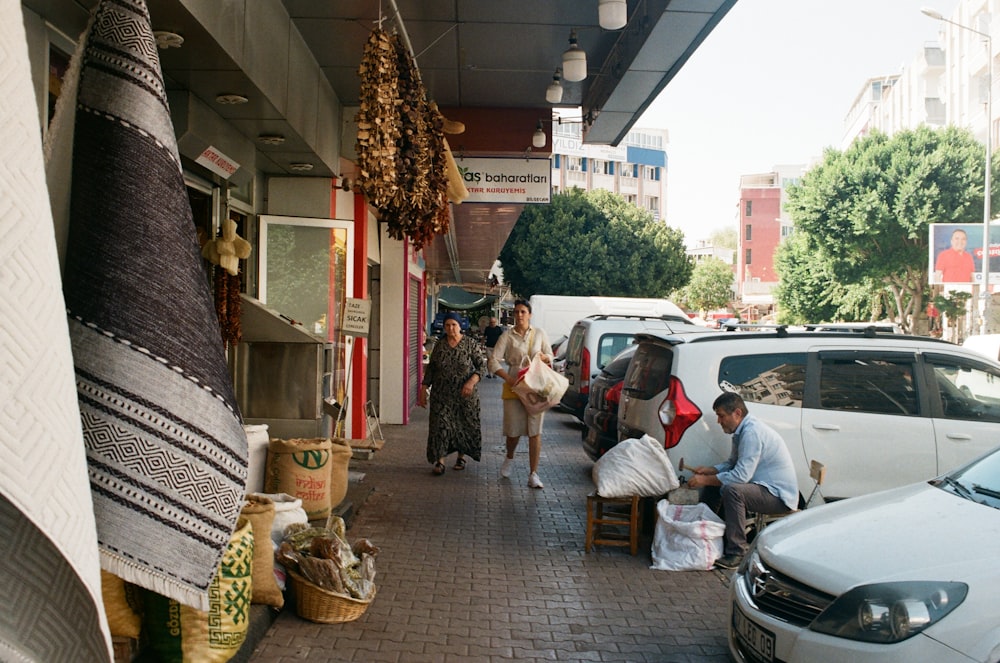 um grupo de pessoas caminhando por uma rua ao lado de carros estacionados