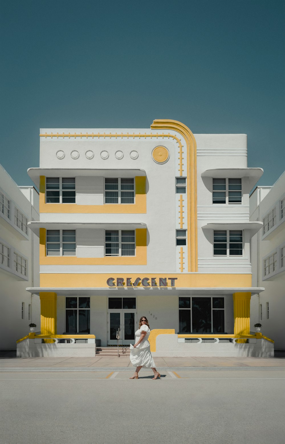 una mujer caminando frente a un edificio blanco y amarillo