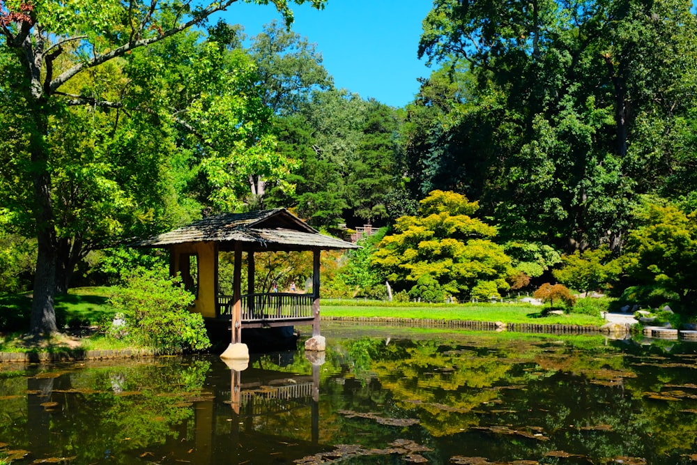 a gazebo in the middle of a pond surrounded by trees