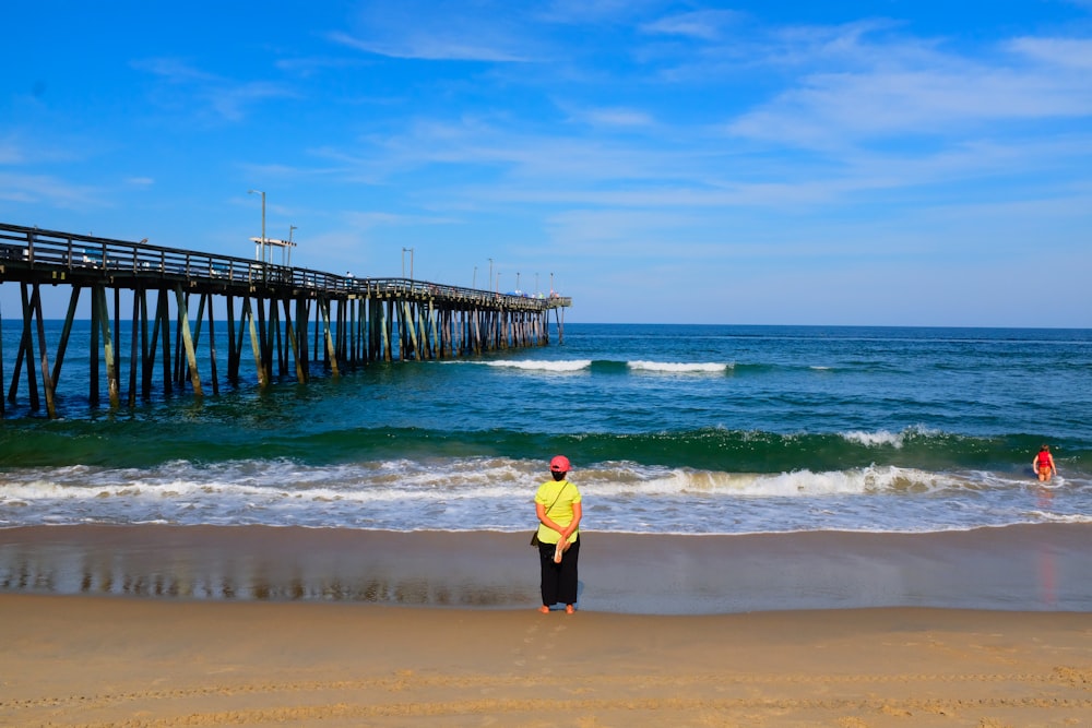 a man standing on top of a sandy beach next to the ocean