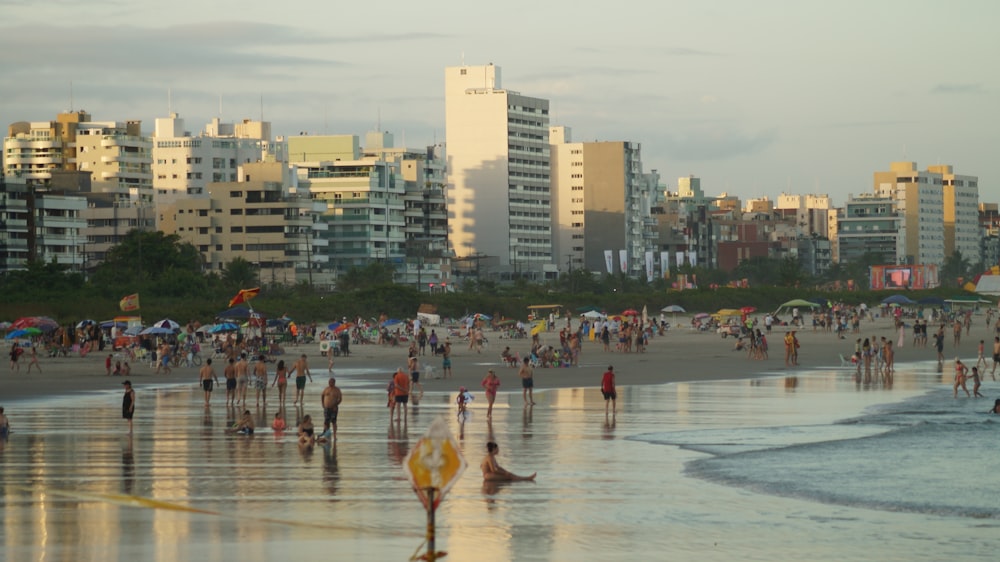 a crowded beach with many people and buildings in the background
