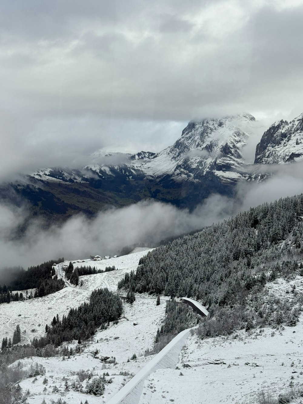 a snow covered mountain with trees and clouds