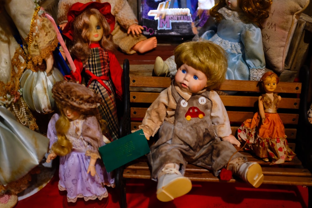 a group of dolls sitting on top of a wooden bench