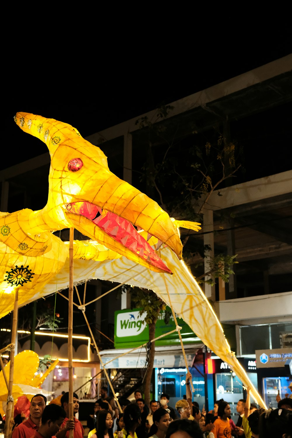 a crowd of people standing around a yellow dragon lantern