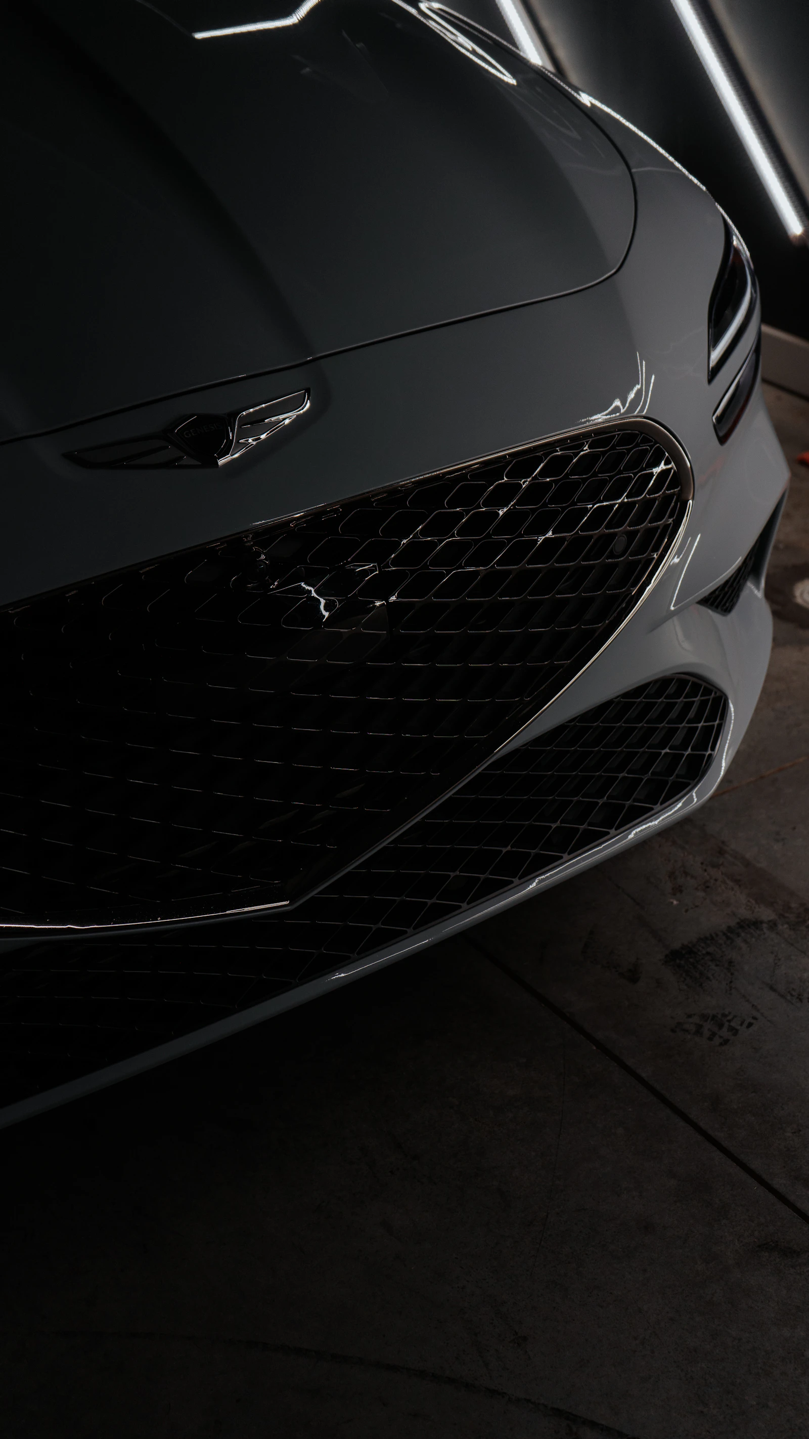 Front of a black sports car before paint correction, dull finish