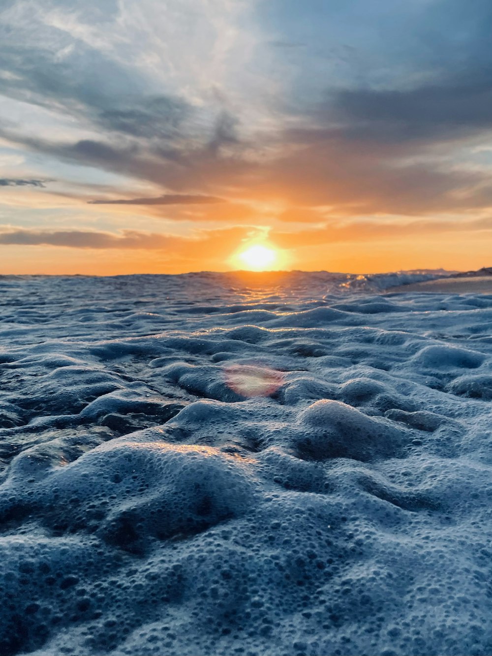 the sun is setting over the ocean on a cloudy day