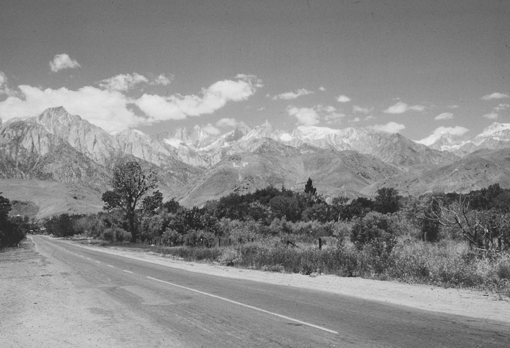 Una foto in bianco e nero di una strada con montagne sullo sfondo