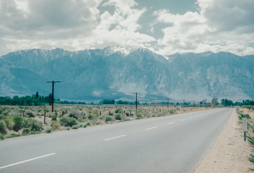 an empty road with mountains in the background