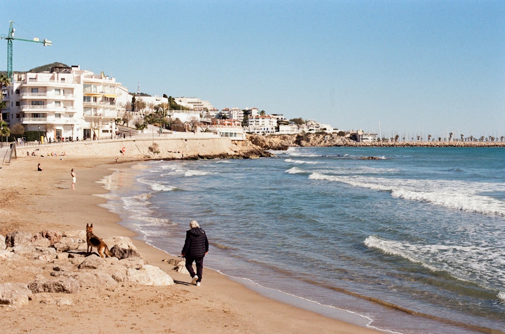 a man walking along a beach next to the ocean