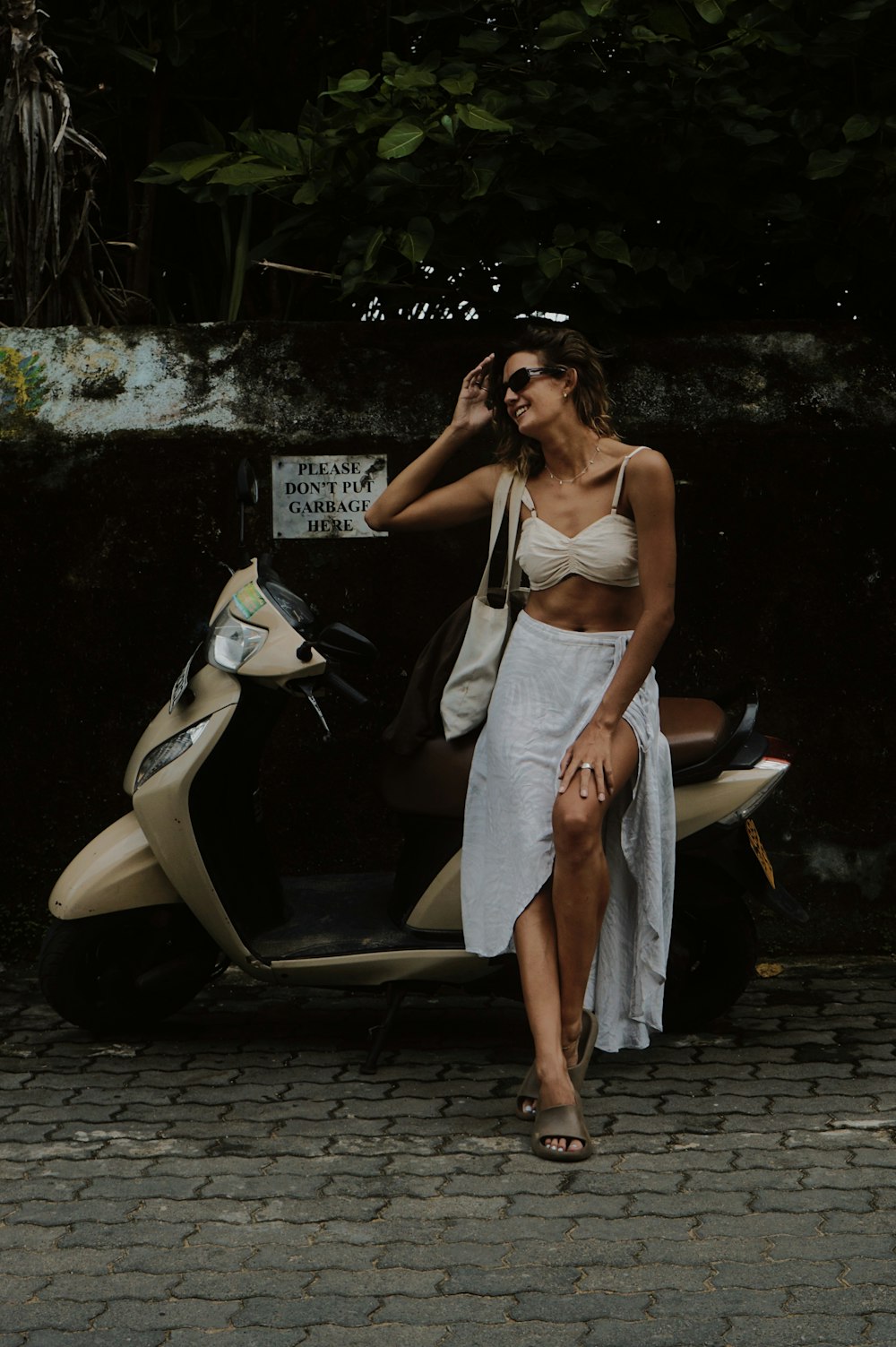 uma mulher em um vestido branco ao lado de uma scooter
