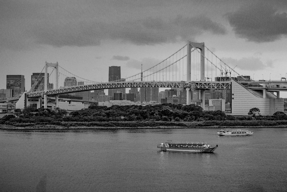 a black and white photo of a bridge and a boat
