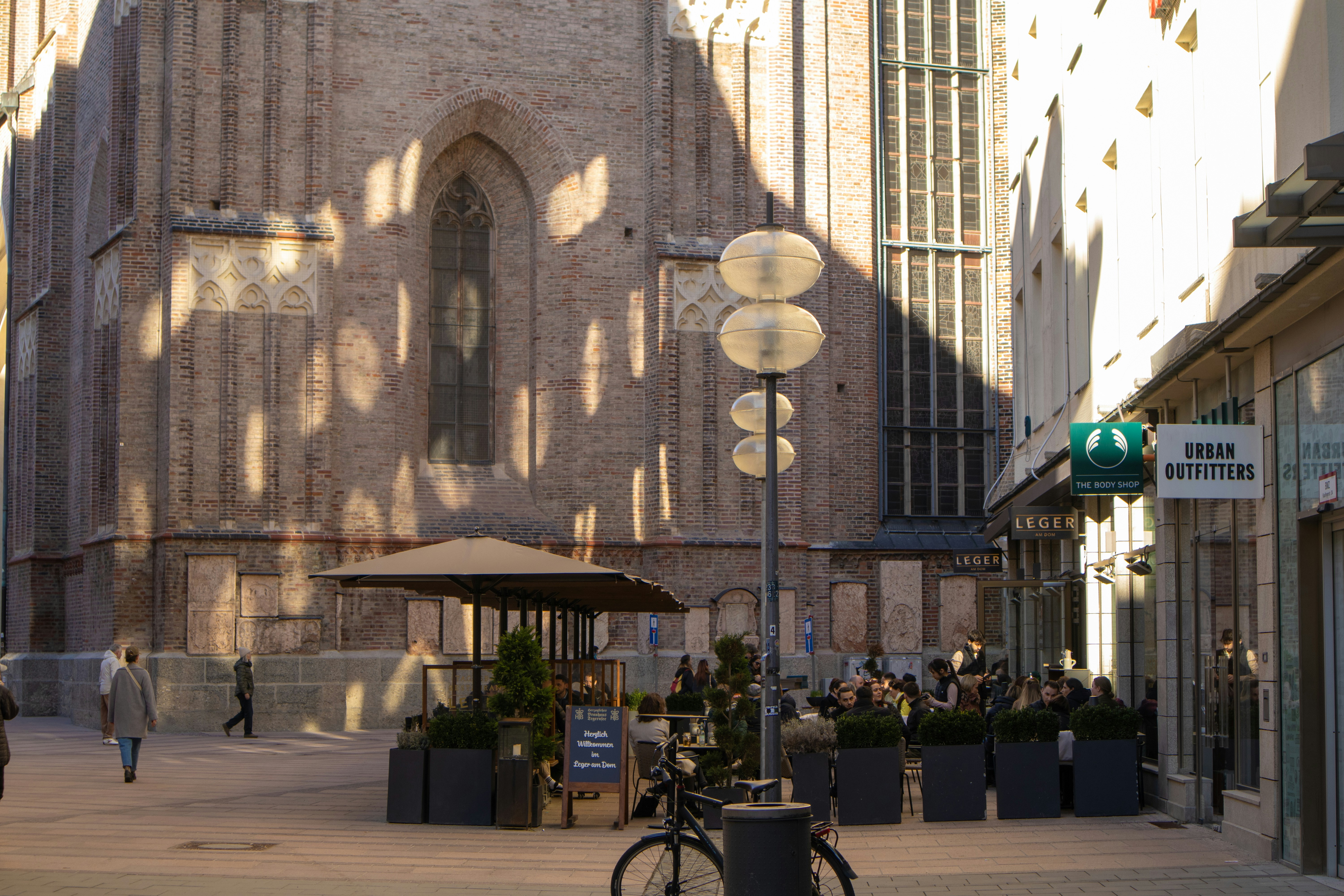 A bike parked along a sunny residential street below a tall building in Munich