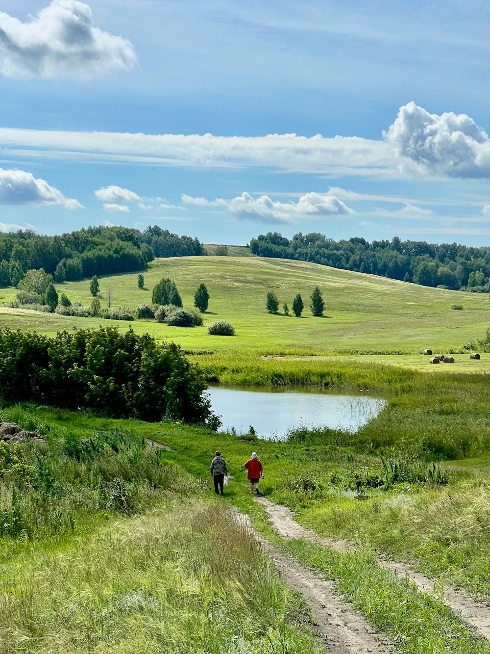 a couple of people walking down a dirt road