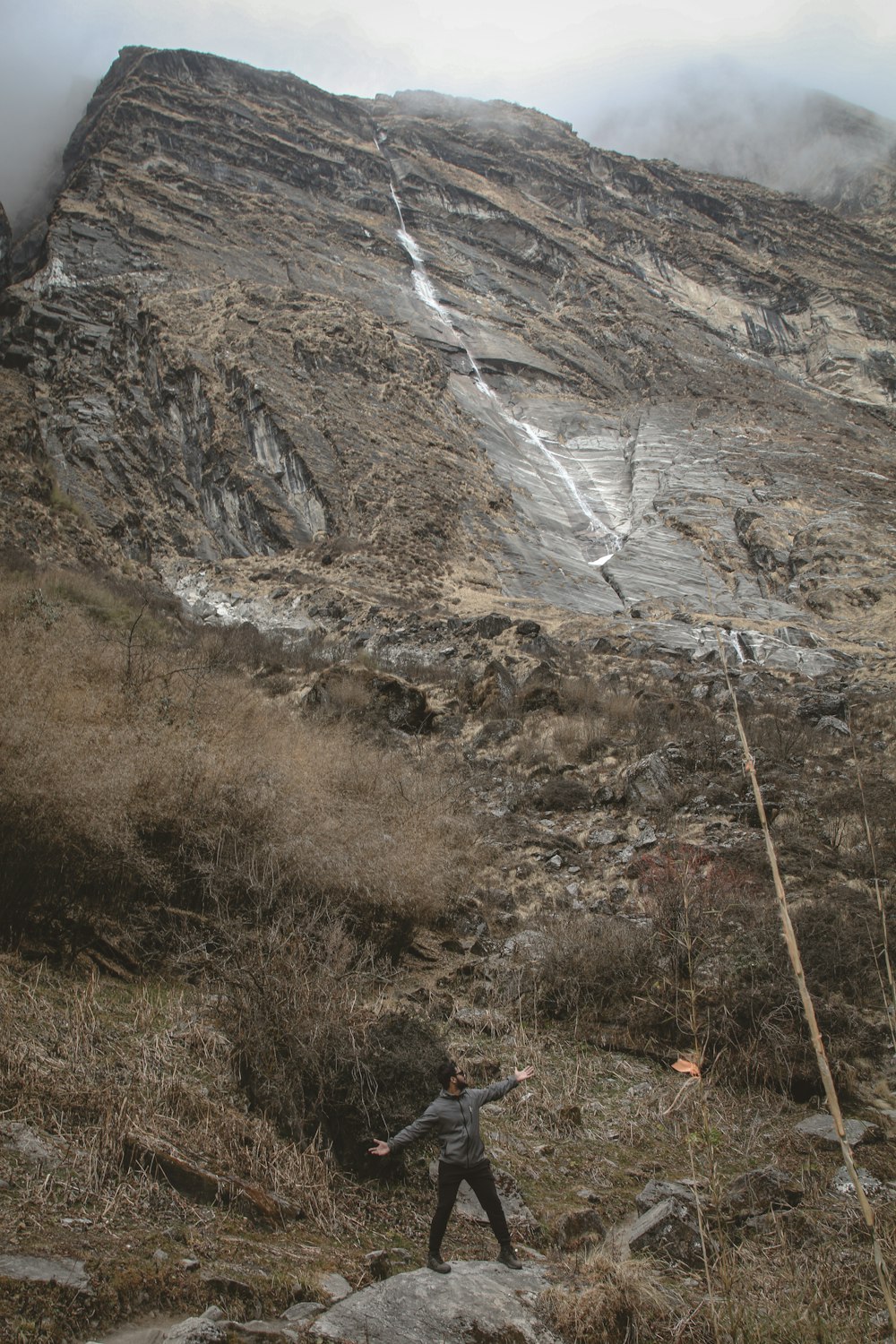 un homme debout au sommet d’une colline rocheuse