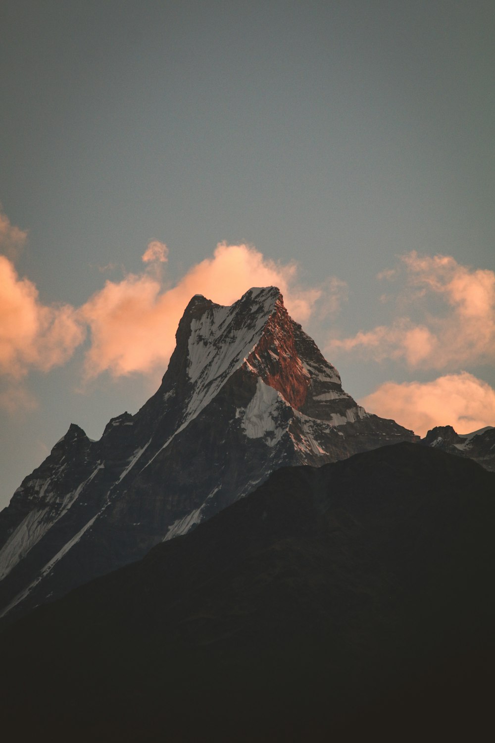 a snow covered mountain with clouds in the background