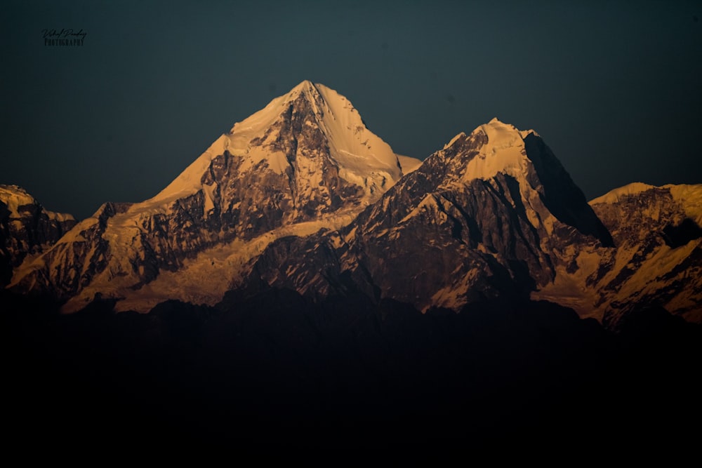 a snow covered mountain with a dark sky in the background