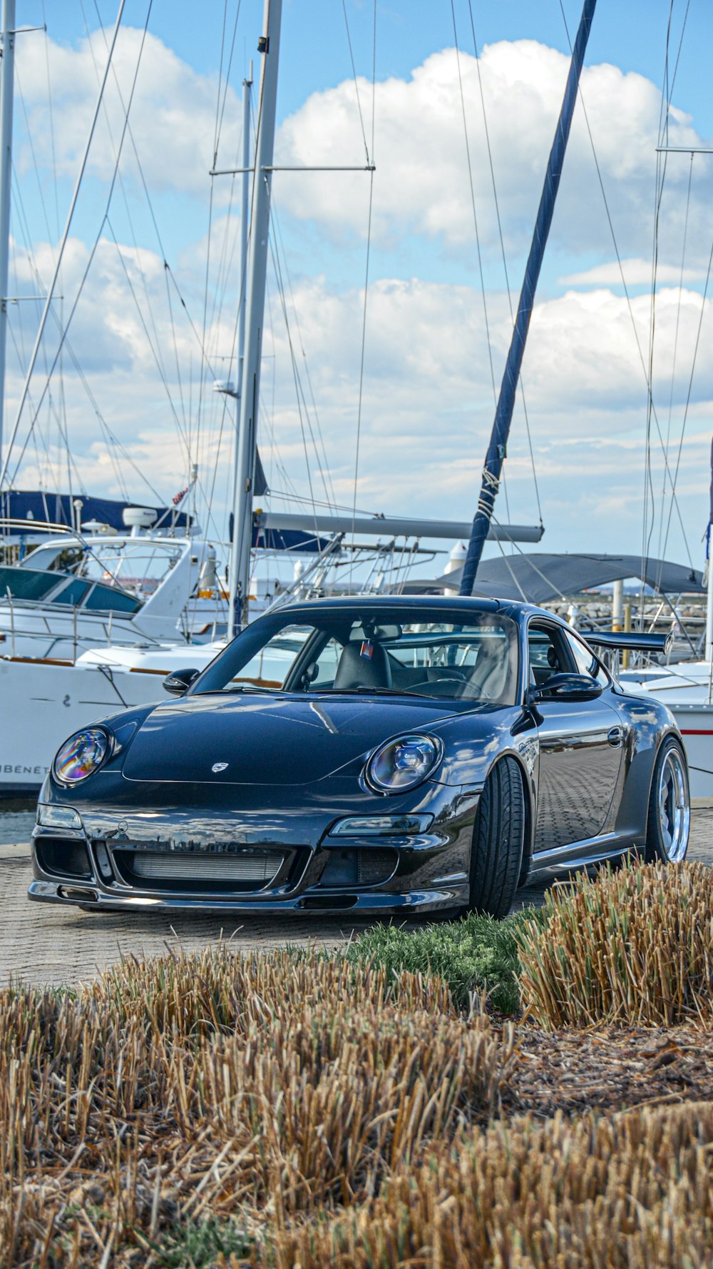 a black sports car parked in front of a boat