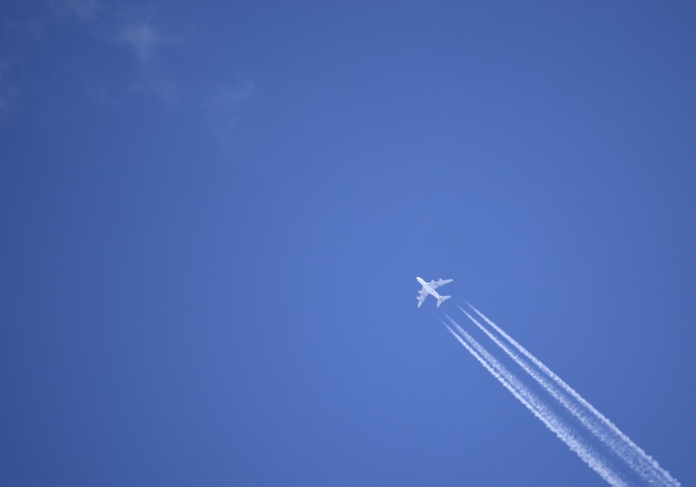 a jet flying through a blue sky leaving a trail of smoke