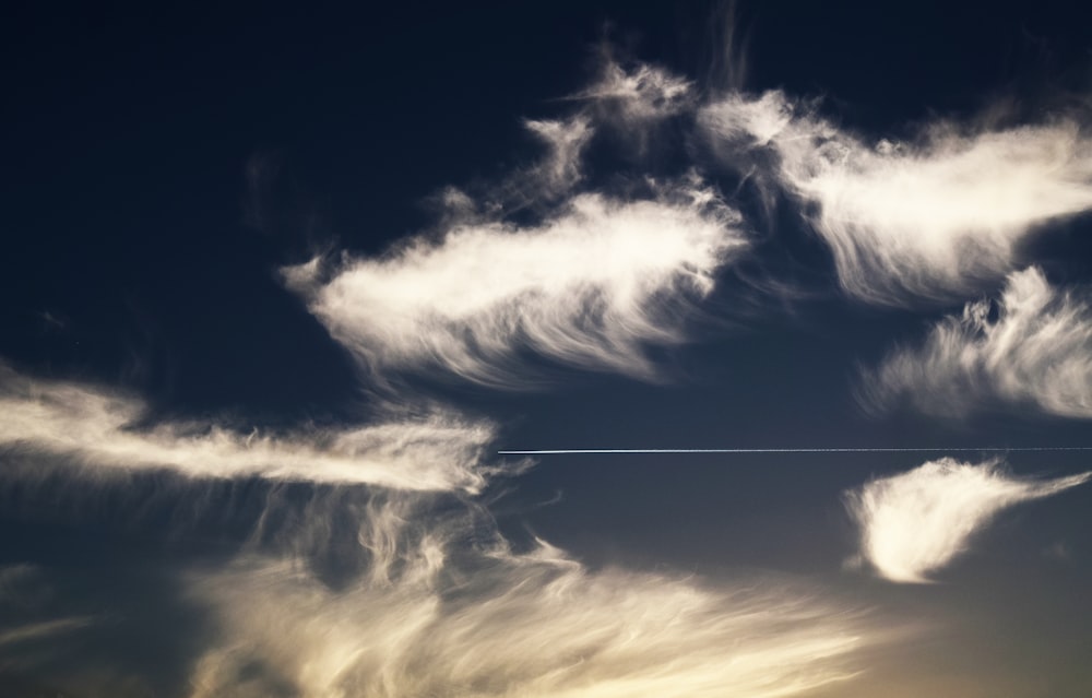 un avión volando a través de un cielo azul nublado