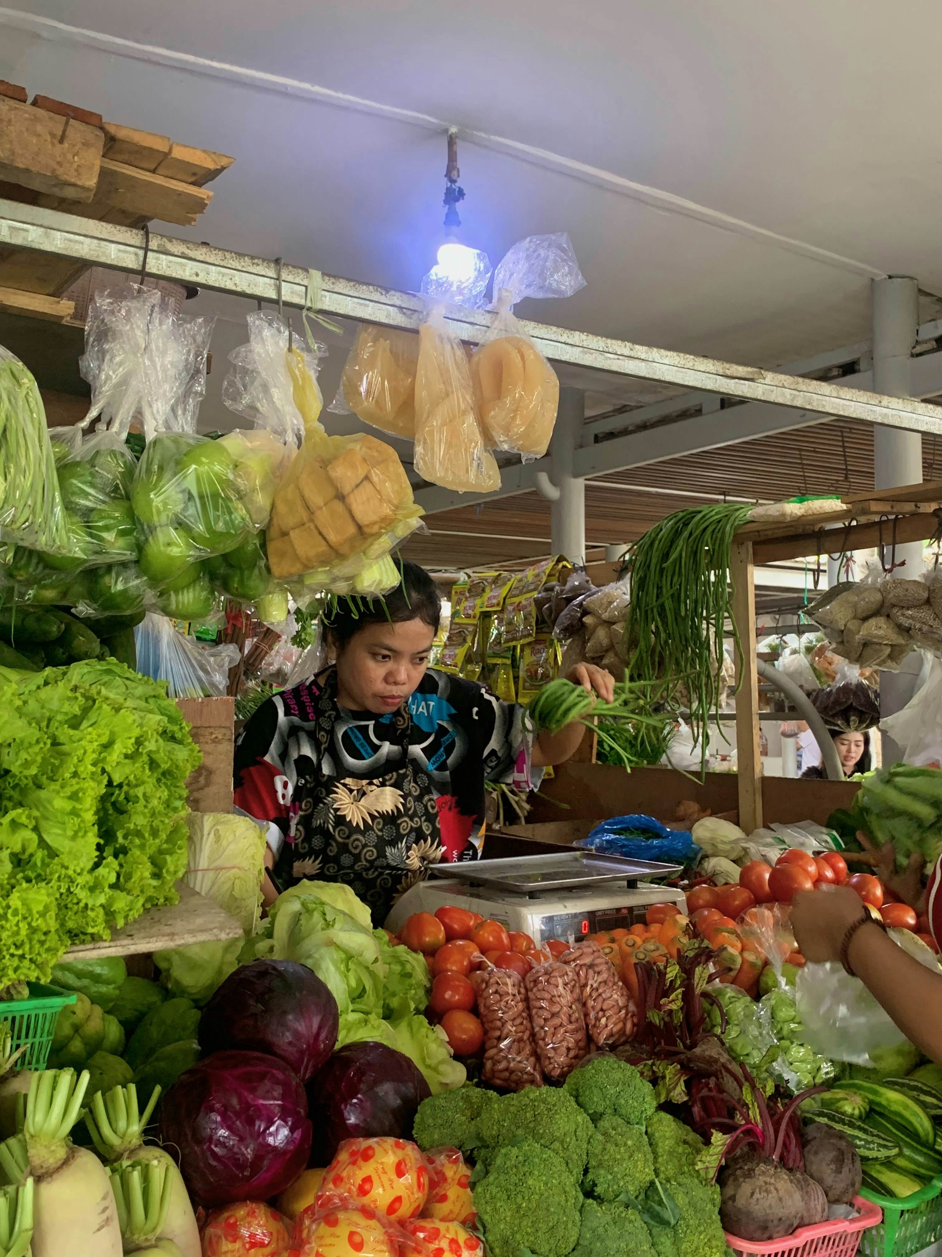 Nigerian woman shopping for fresh vegetables and fruits at a vibrant local market stall, warm natural light