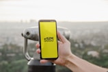 a person holding up a cell phone with a logo on it