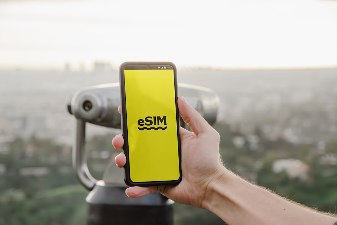 a person holding up a cell phone with a logo on it, Android phone user showcasing the eSIM digital interface
