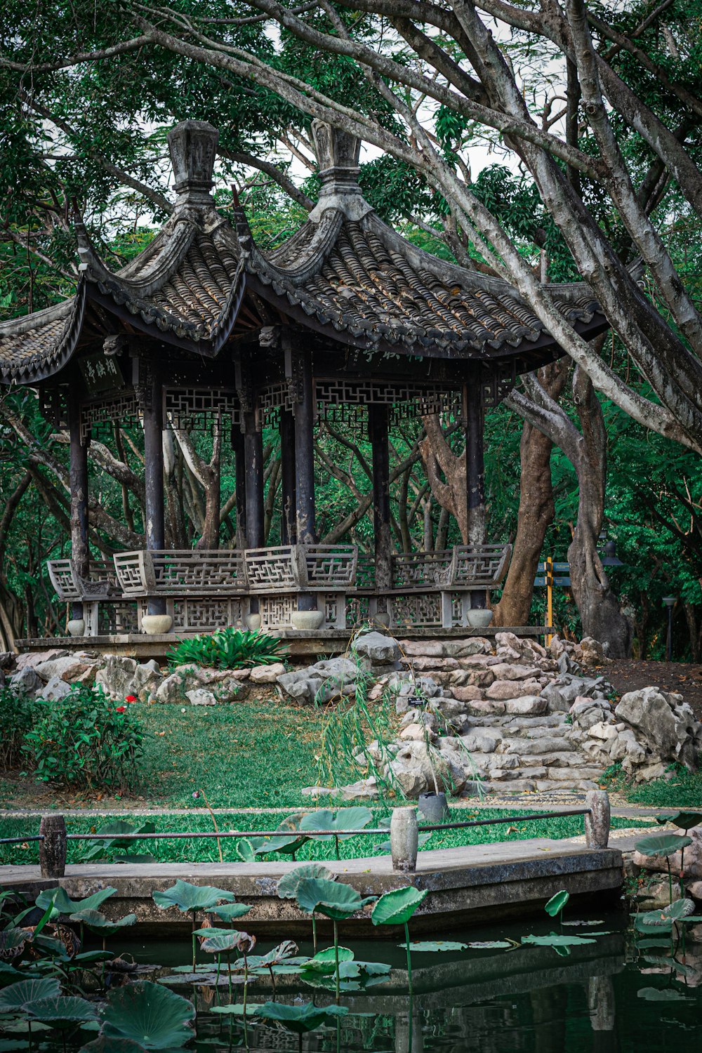 a gazebo in the middle of a pond surrounded by trees