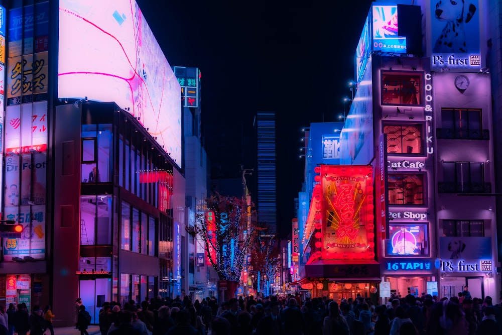 a crowd of people walking down a street at night