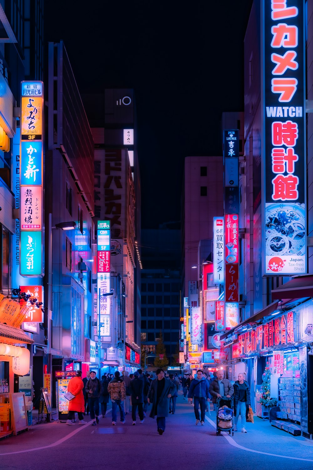 a group of people walking down a street at night