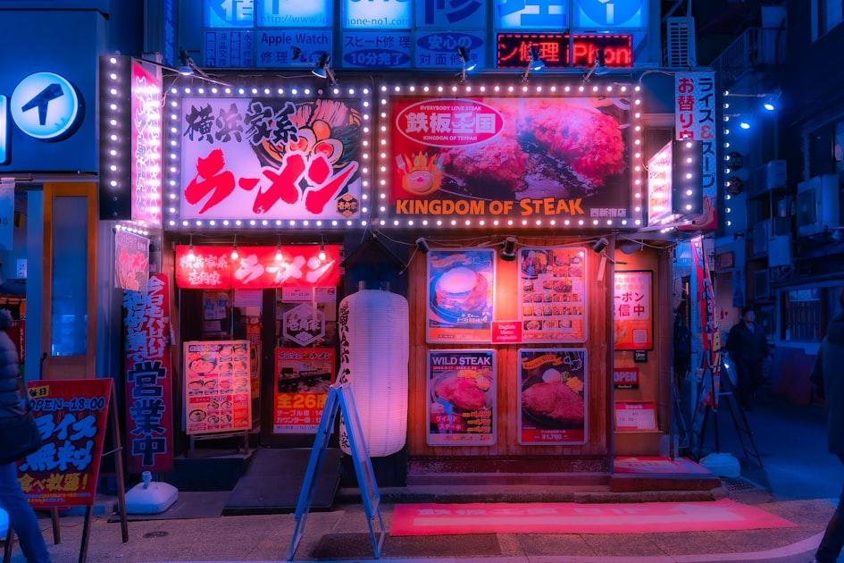 A city street corner at night covered in neon signs and stacked advertisements competing for attention