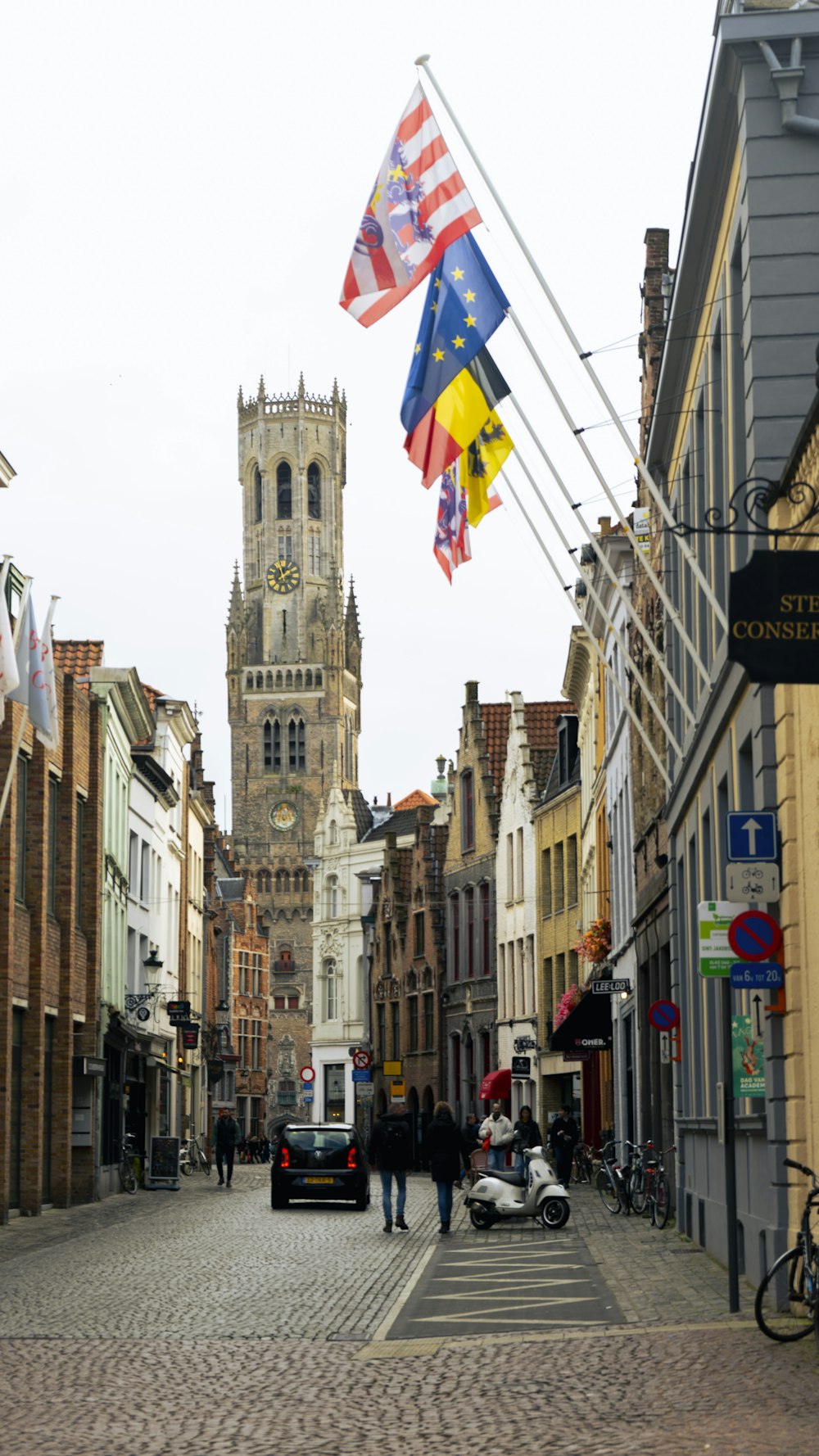 a cobblestone street lined with buildings and flags