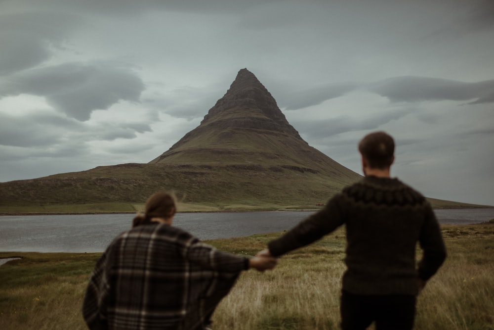 two people holding hands in front of a mountain