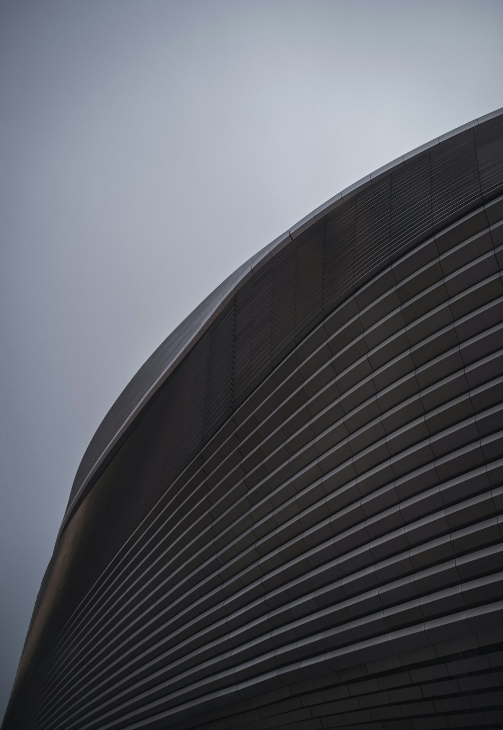 a tall building with a curved roof on a cloudy day