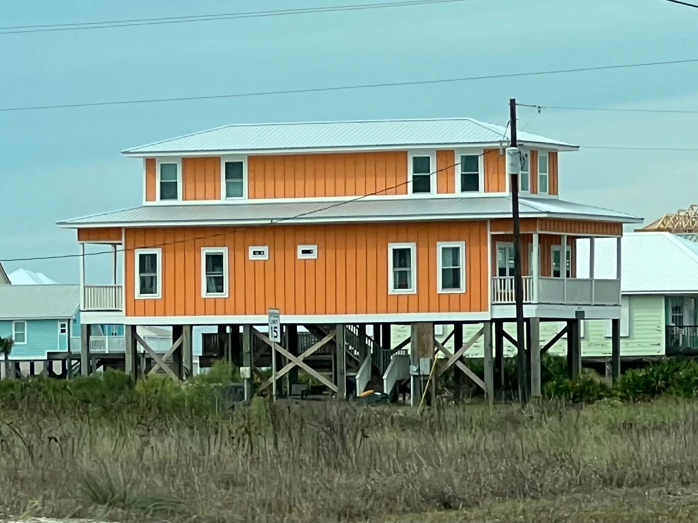 An orange house raised on stilts above the ground