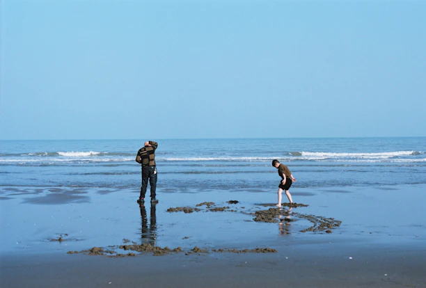 a couple of people standing on top of a beach