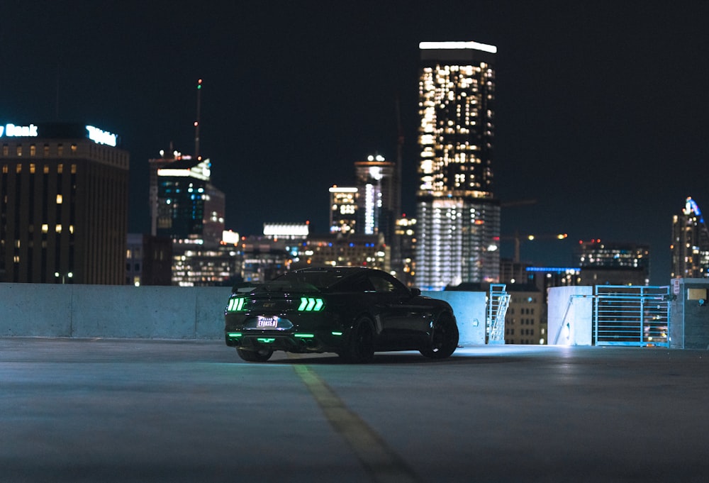 a black sports car driving down a city street at night