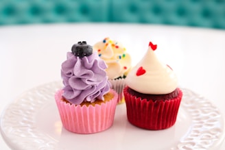 a white plate topped with three cupcakes covered in frosting