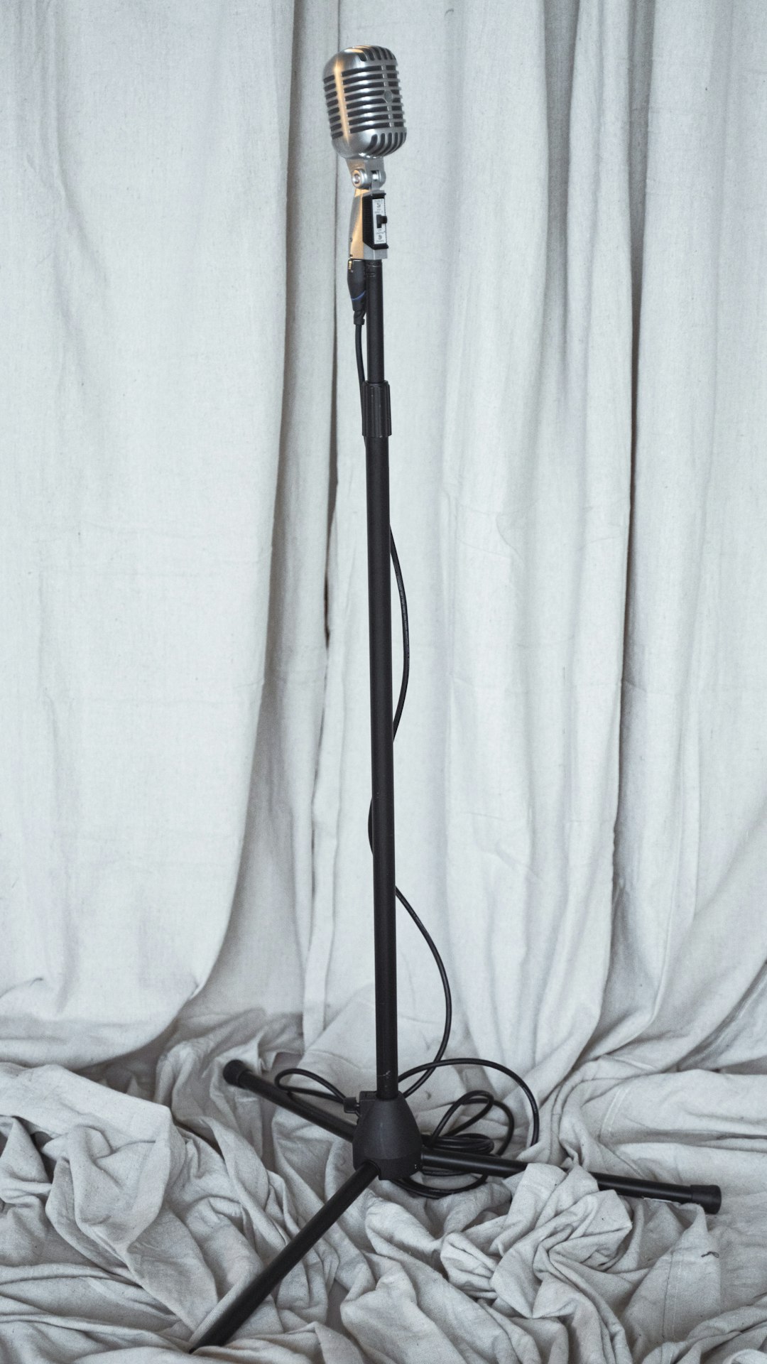 Vintage podcast microphone on a stand with a curtain background