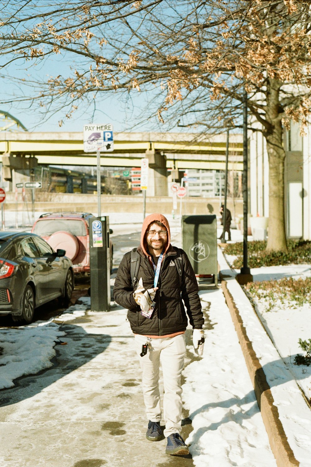 a man walking down a sidewalk in the snow