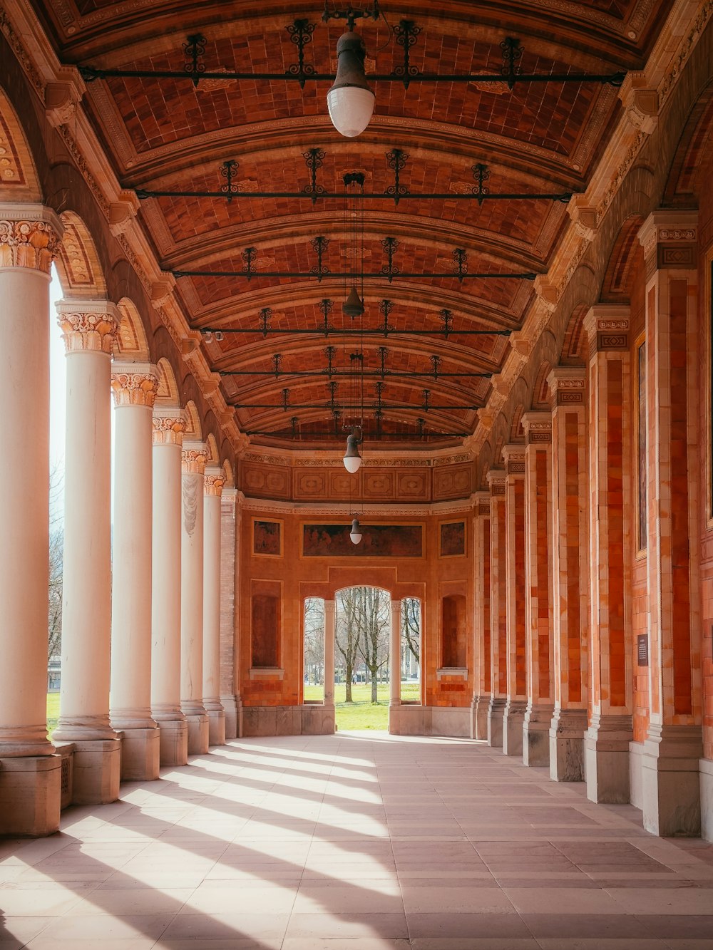 a long hallway with columns and a light fixture hanging from the ceiling