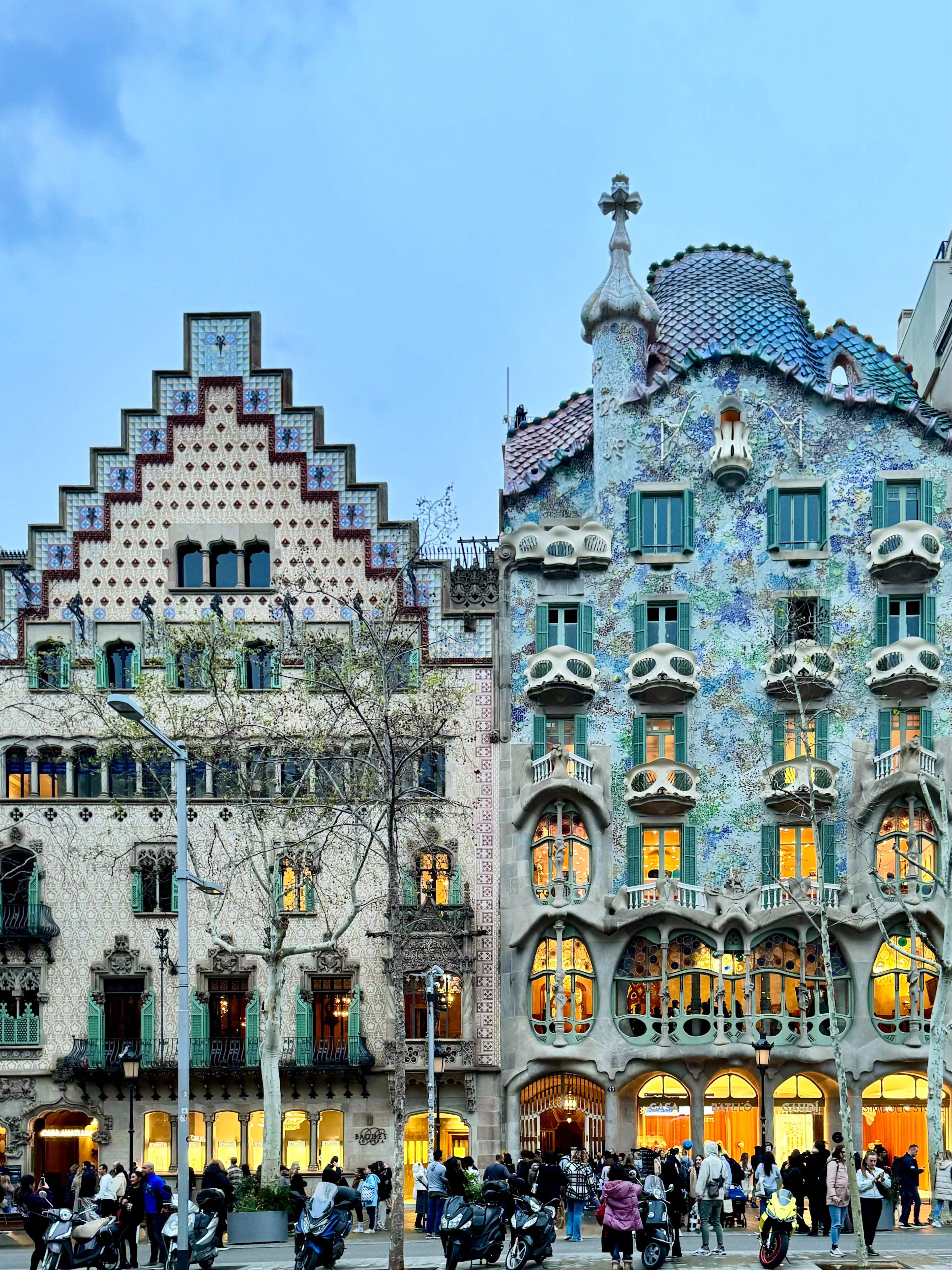 Casa Amatller and Casa Batllo's Modernista facades lit up on Passeig de Gracia at dusk.