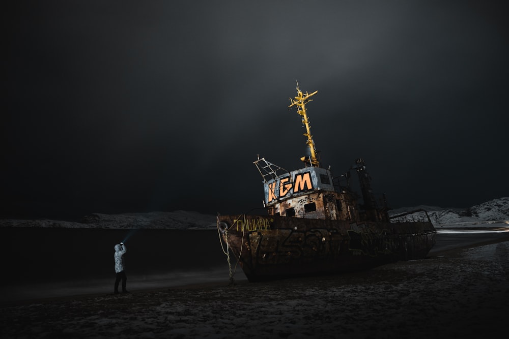 a man standing next to a boat on a beach