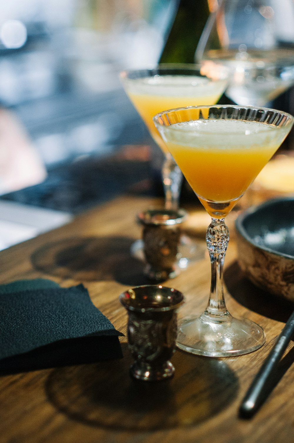 a wooden table topped with two glasses filled with drinks