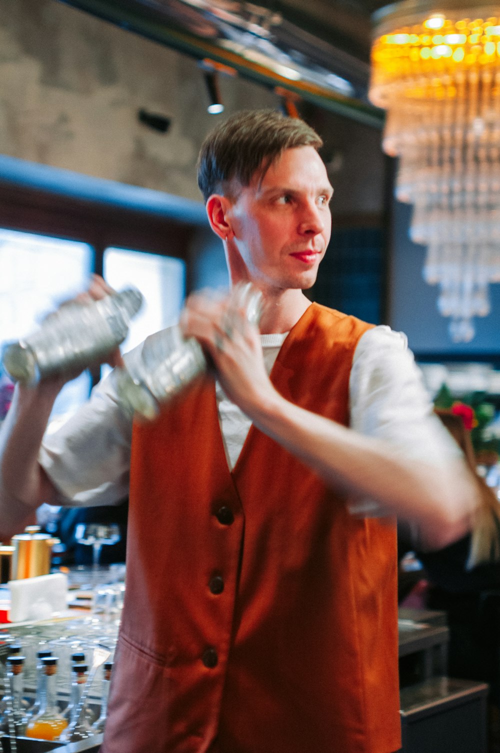 a man in an orange vest pouring drinks at a bar
