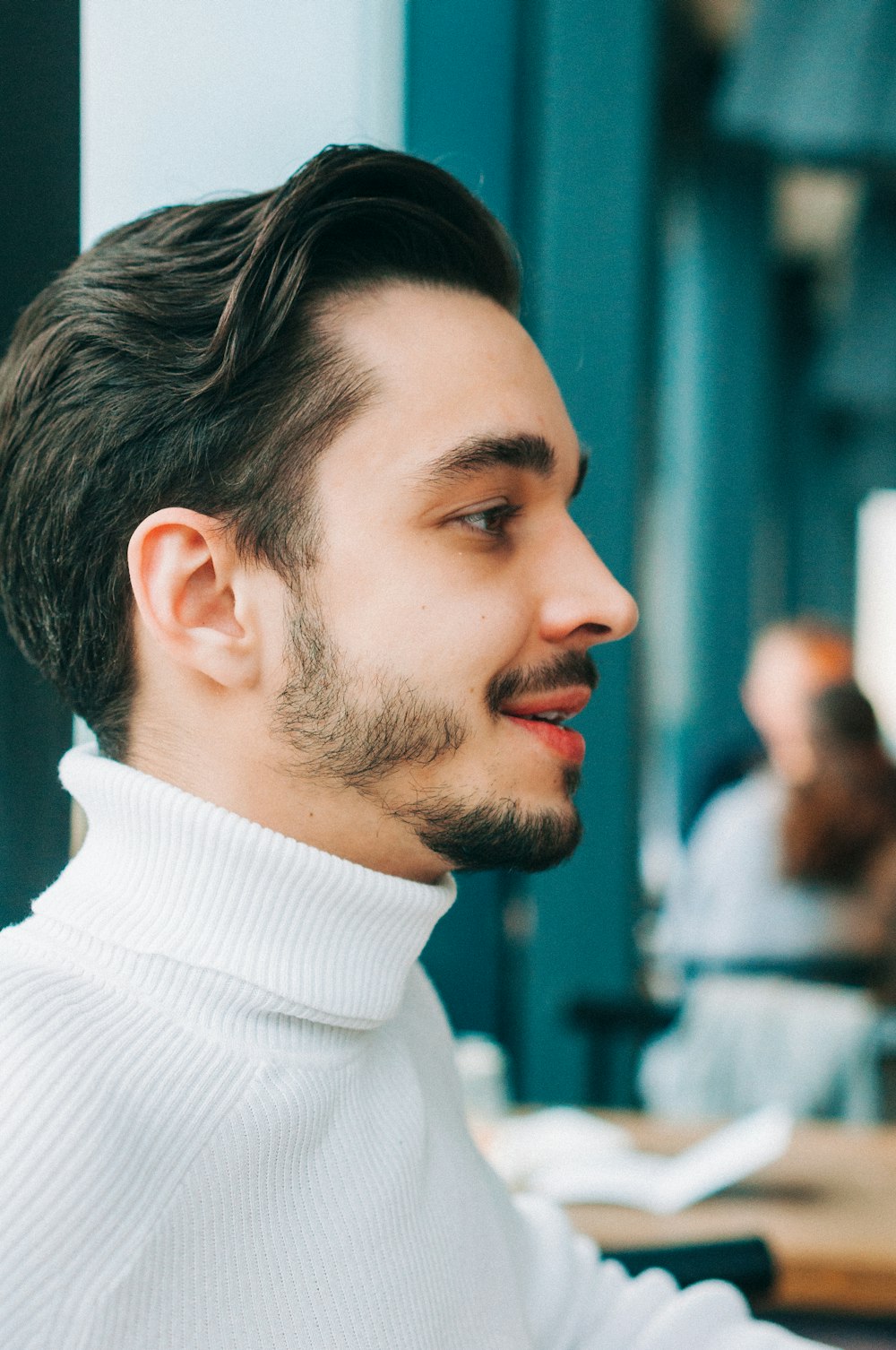 a man with a goatee and a white turtle neck sweater