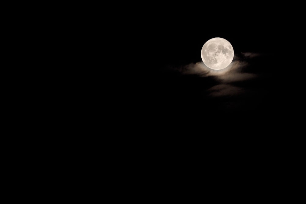 a full moon is seen in the dark sky