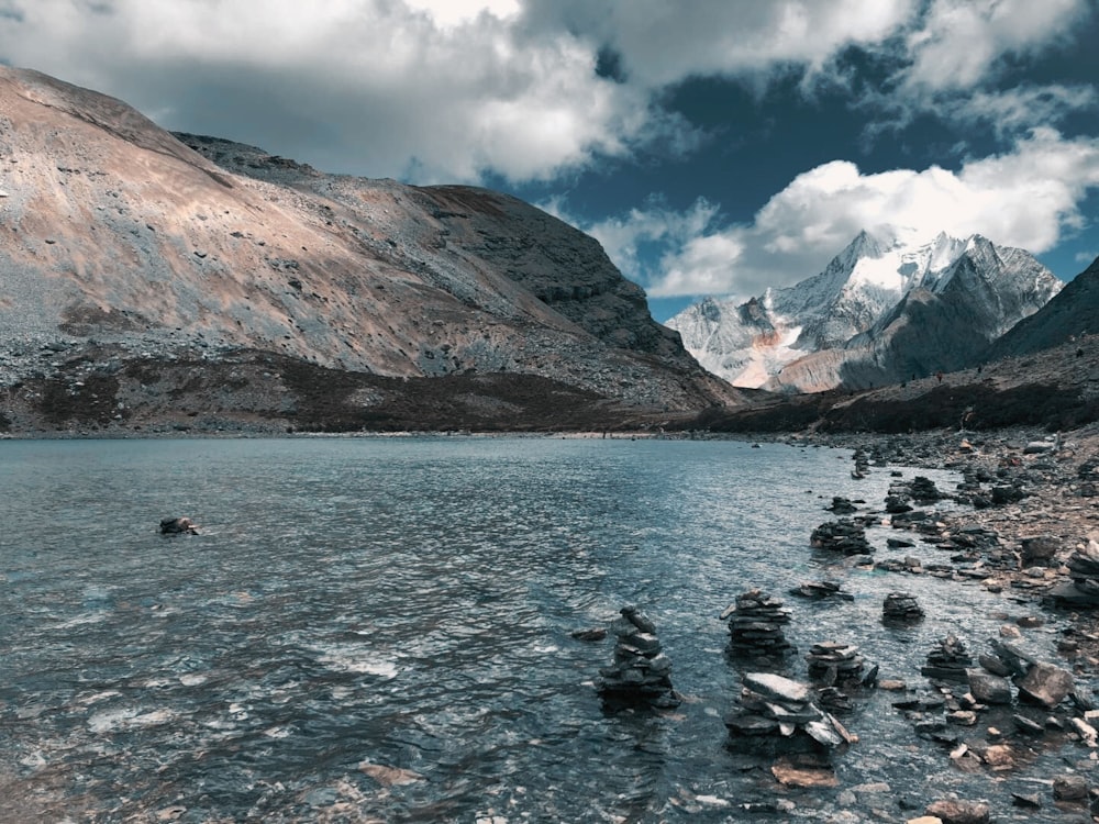 Ein See, umgeben von Bergen und Felsen unter einem bewölkten Himmel